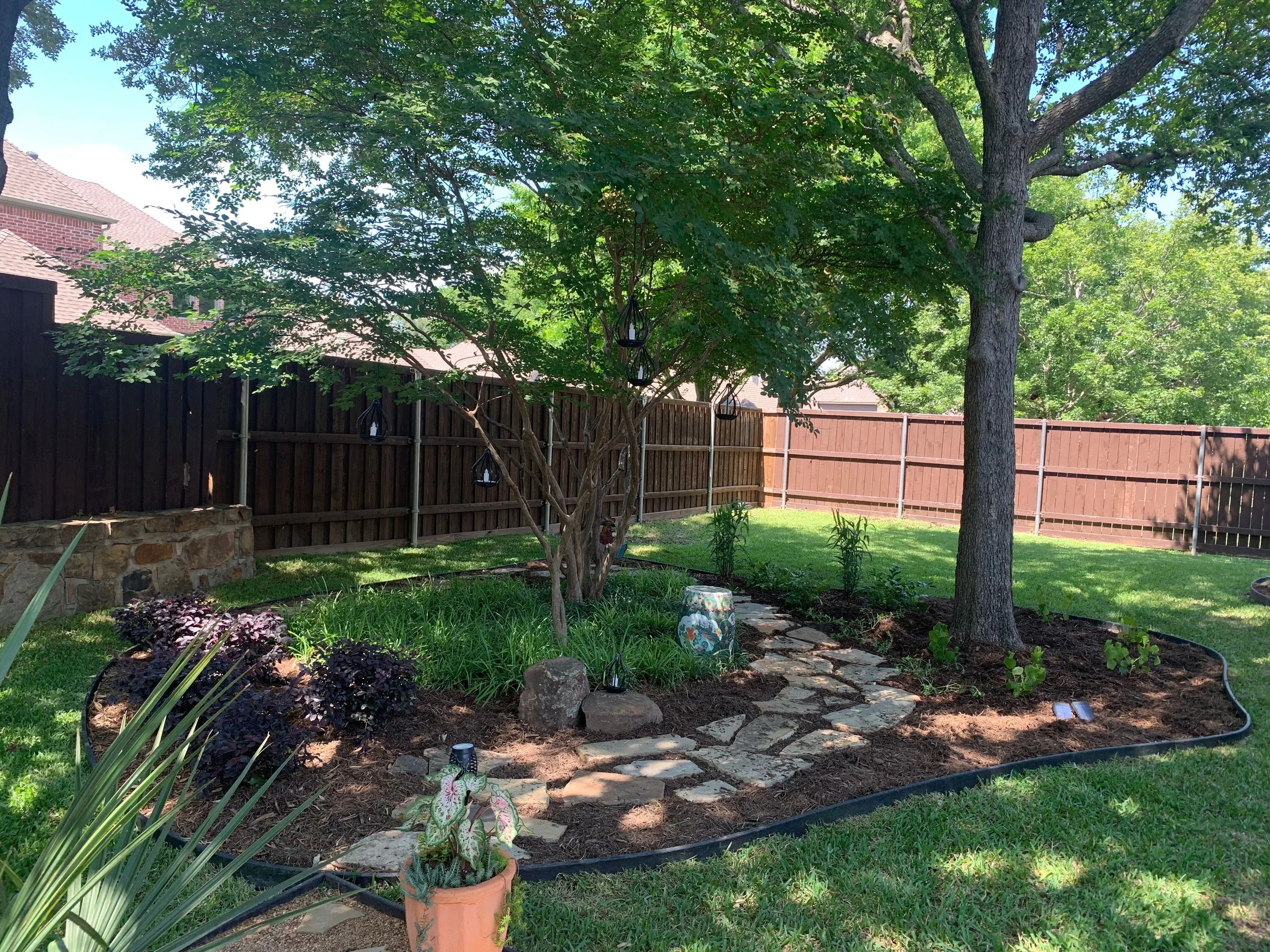 Landscape: Client's existing fun sculptures and lovely colorful pots are beautifully displayed in front of the new planting bed with new additional liriopes, loropetalums, and turks' caps. Elegant LED lighting provided by Client enhances the landscap