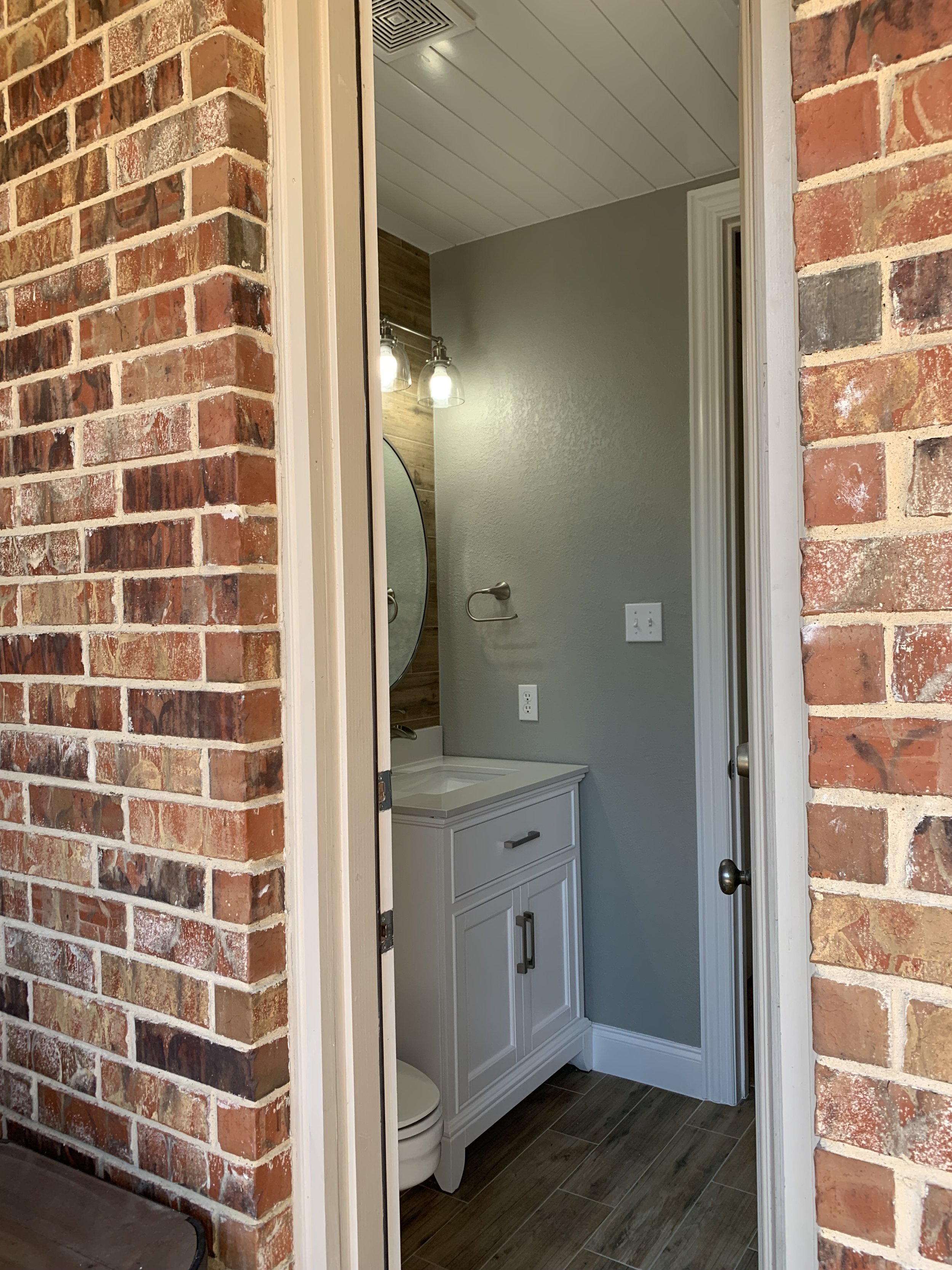 Half Bathroom: Continuous floor and wall tiling featuring custom wood ceiling for a refined coastal aesthetic