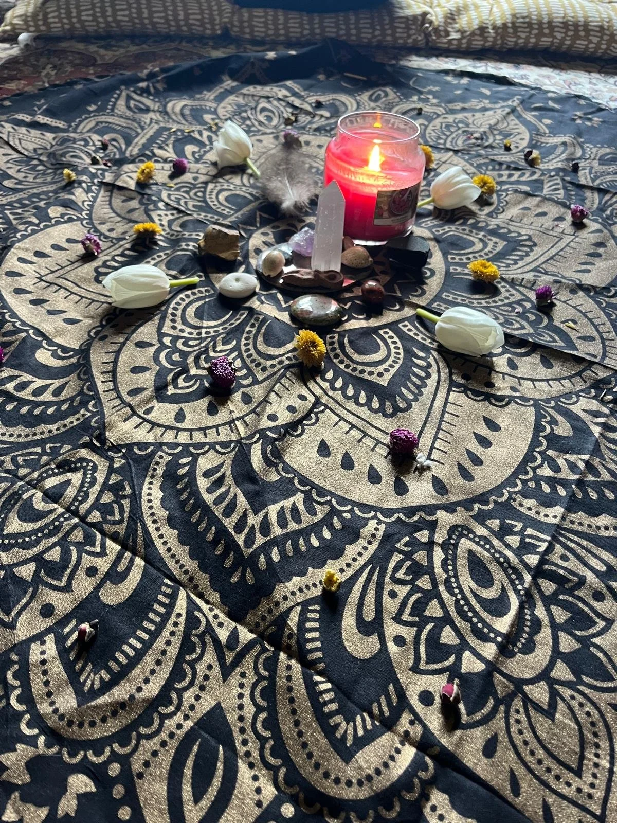 Mother blessing ceremony or blessingway hosted by Your Doula Aurelia. Image shows a lighted candle surrounded by an arranged circle or crystals, pebbles and flowers