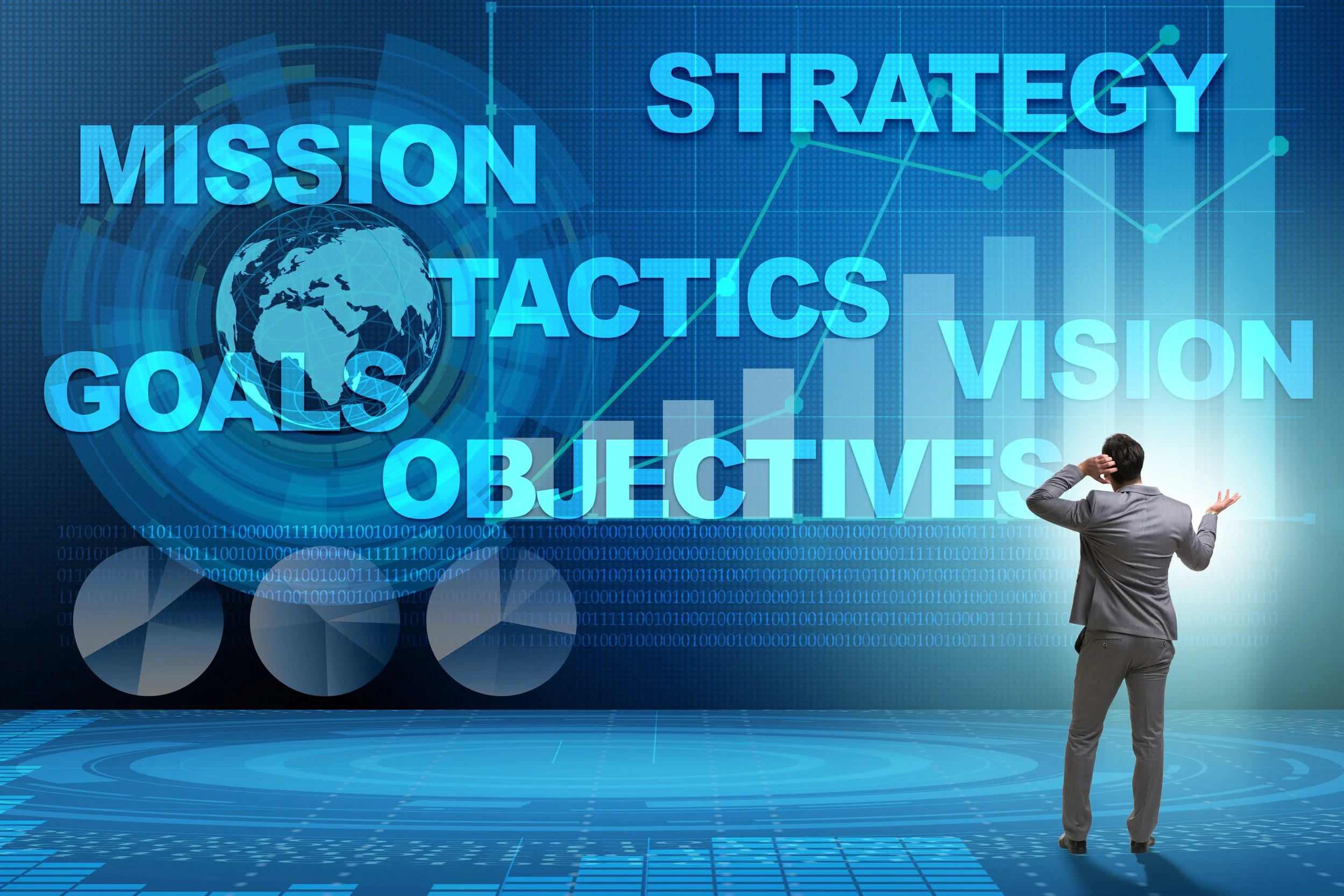 A man in a suit looks at a large digital screen displaying words like 'mission', 'strategy', 'goals', 'objectives', and 'vision', along with global maps, charts, and binary code, in a futuristic setting.