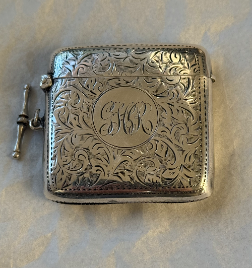 Silver ornate Vesta case with engraved initials 'H C' and a decorative floral pattern.