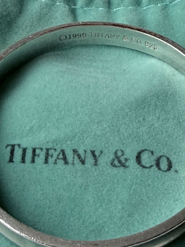Close-up of a Tiffany & Co. jewelry box with a silver ring inside, displaying the Tiffany & Co. logo and copyright date of 1999.