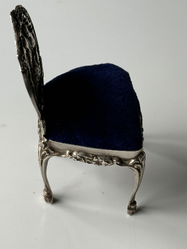 Small ornate chair with a dark blue cushion and a decorative backrest.