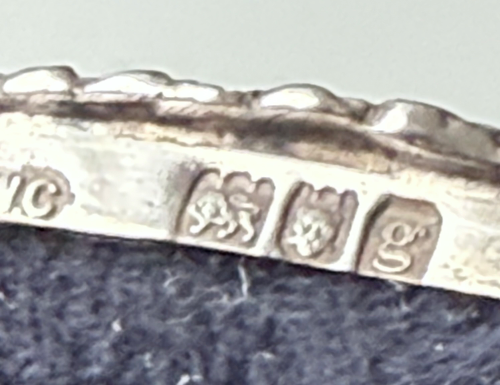 Close-up of a silver chair showing its engraved hallmarks.
