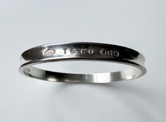 Genuine Tiffany & Co. sterling silver bangle bracelet with classic “1837” and Tiffany marks.
Comes with original pouch/box elements.
