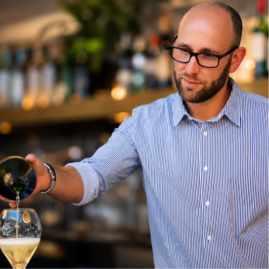 Man pouring white wine into a glass at a bar or restaurant
