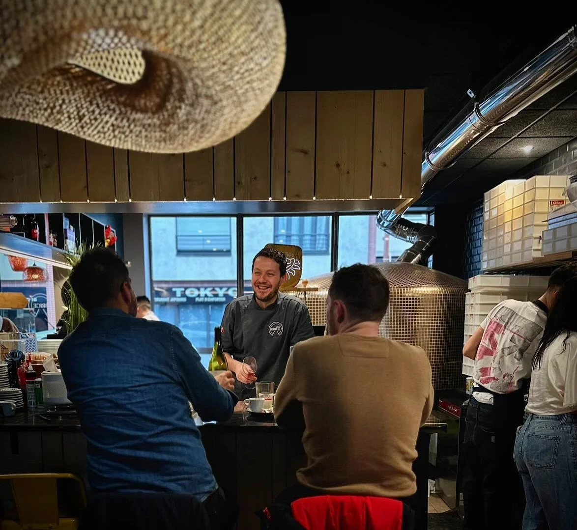 People gathered at a bar in a restaurant, engaging in conversation and socializing.