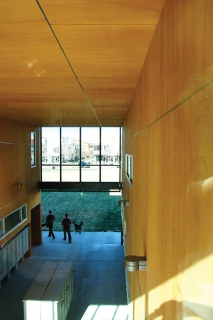 View from an indoor staircase looking towards glass doors and outdoor area with people walking.