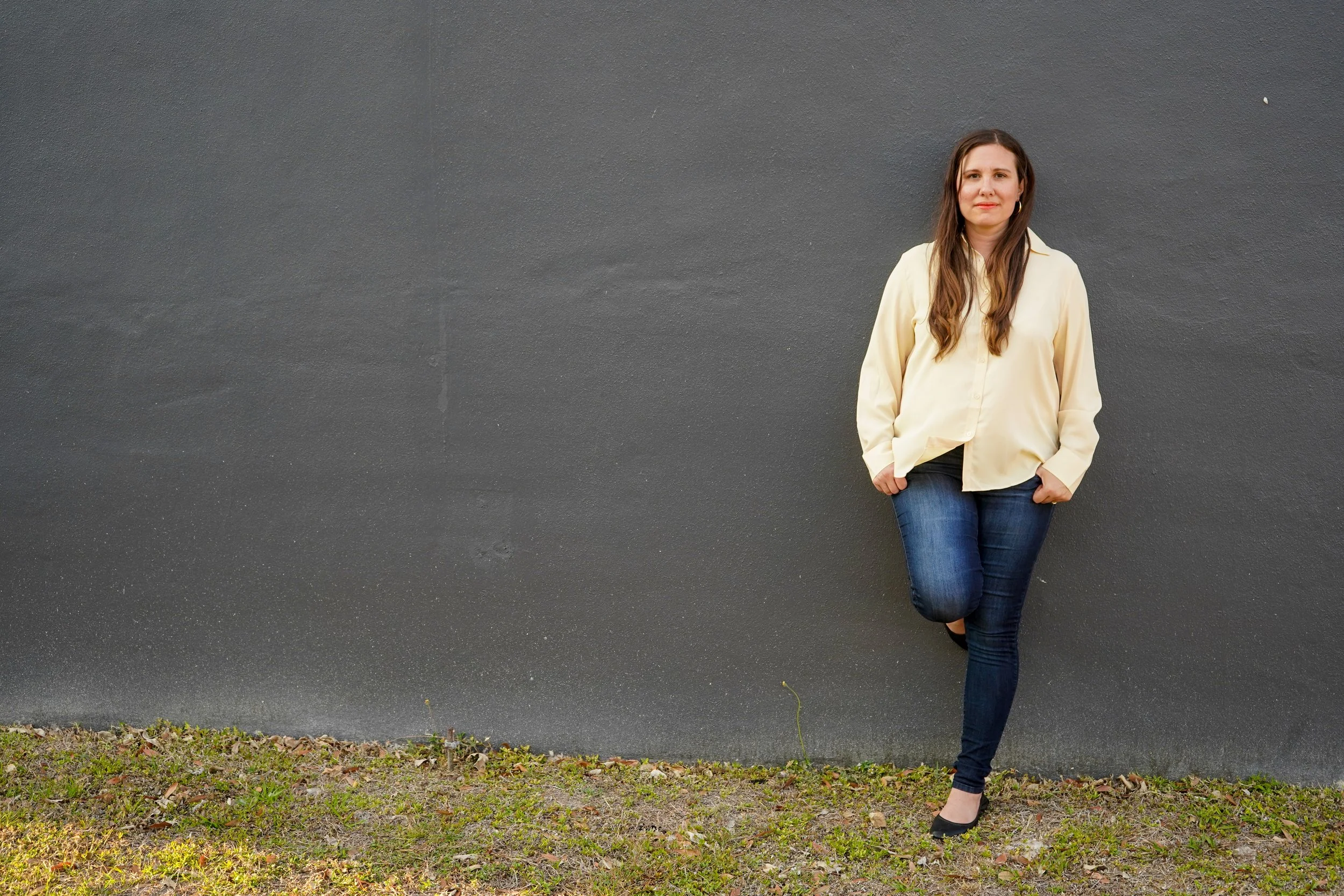 Author Katie Parsons stands against a gray wall outside