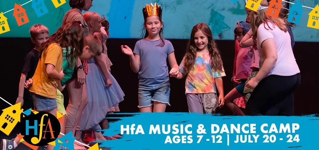 Children dancing and playing at a music and dance camp with colorful decorations and a woman guiding them.