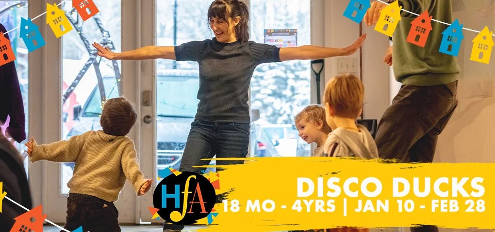 Children and a woman dancing indoors celebrating a disco-themed event, with colored house-shaped banners hanging above.