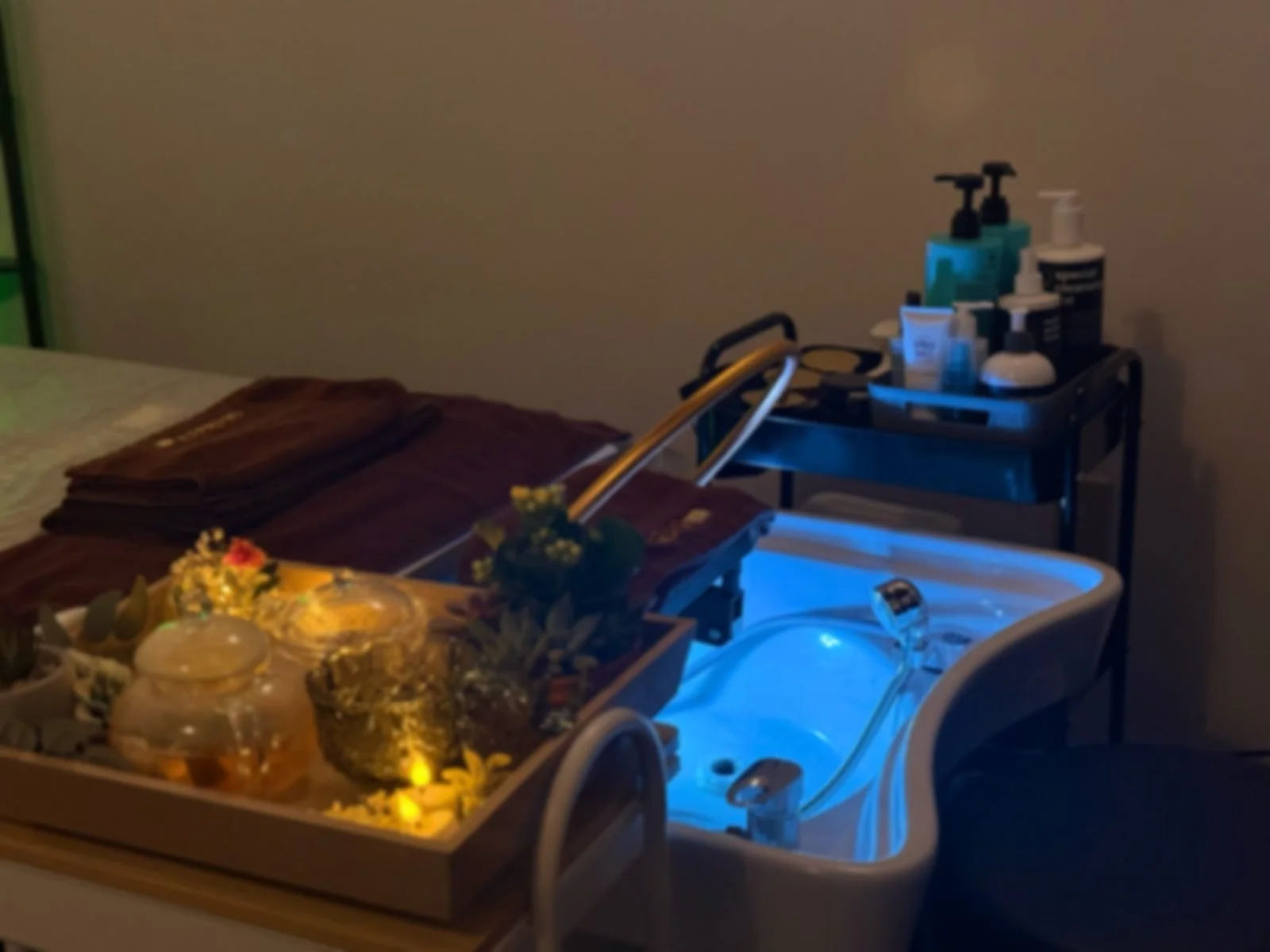 Head spa treatment station with a blue-lit wash basin and candlelit tray
