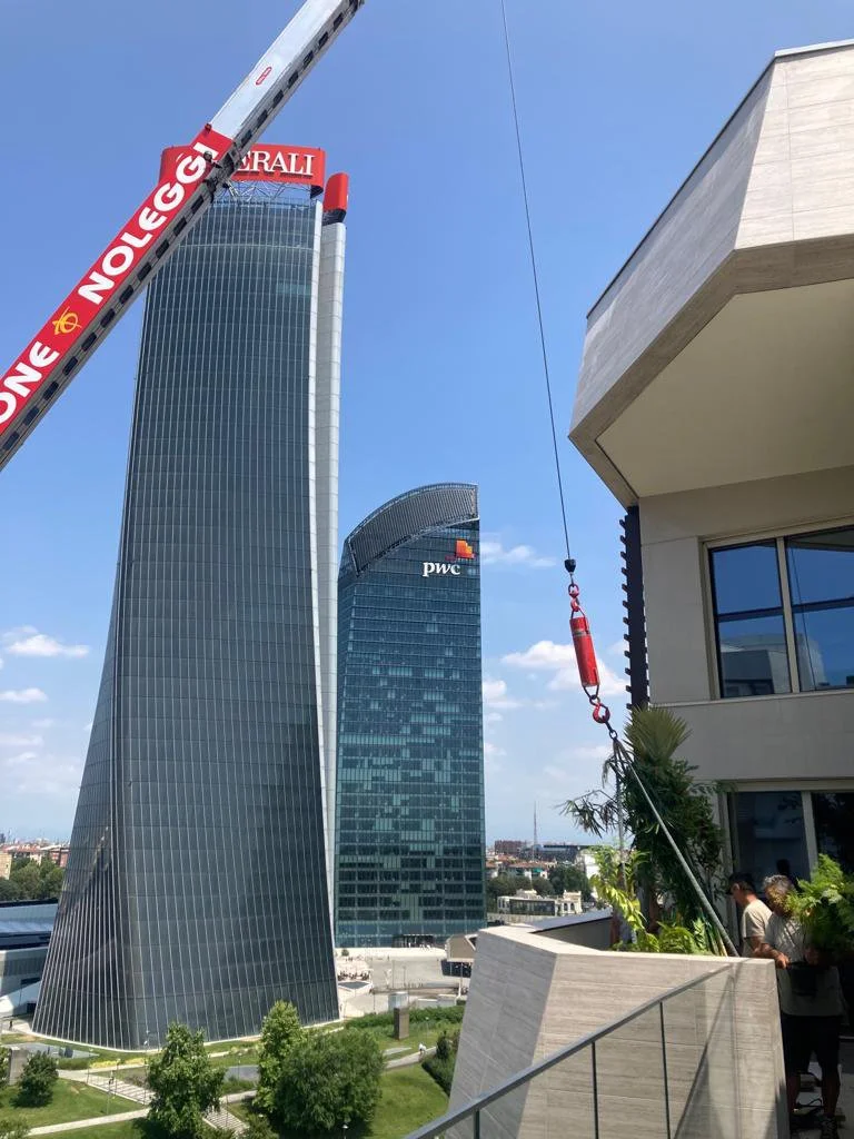 Cityscape featuring modern skyscrapers with PwC logo, construction crane, and building terrace with people and greenery.