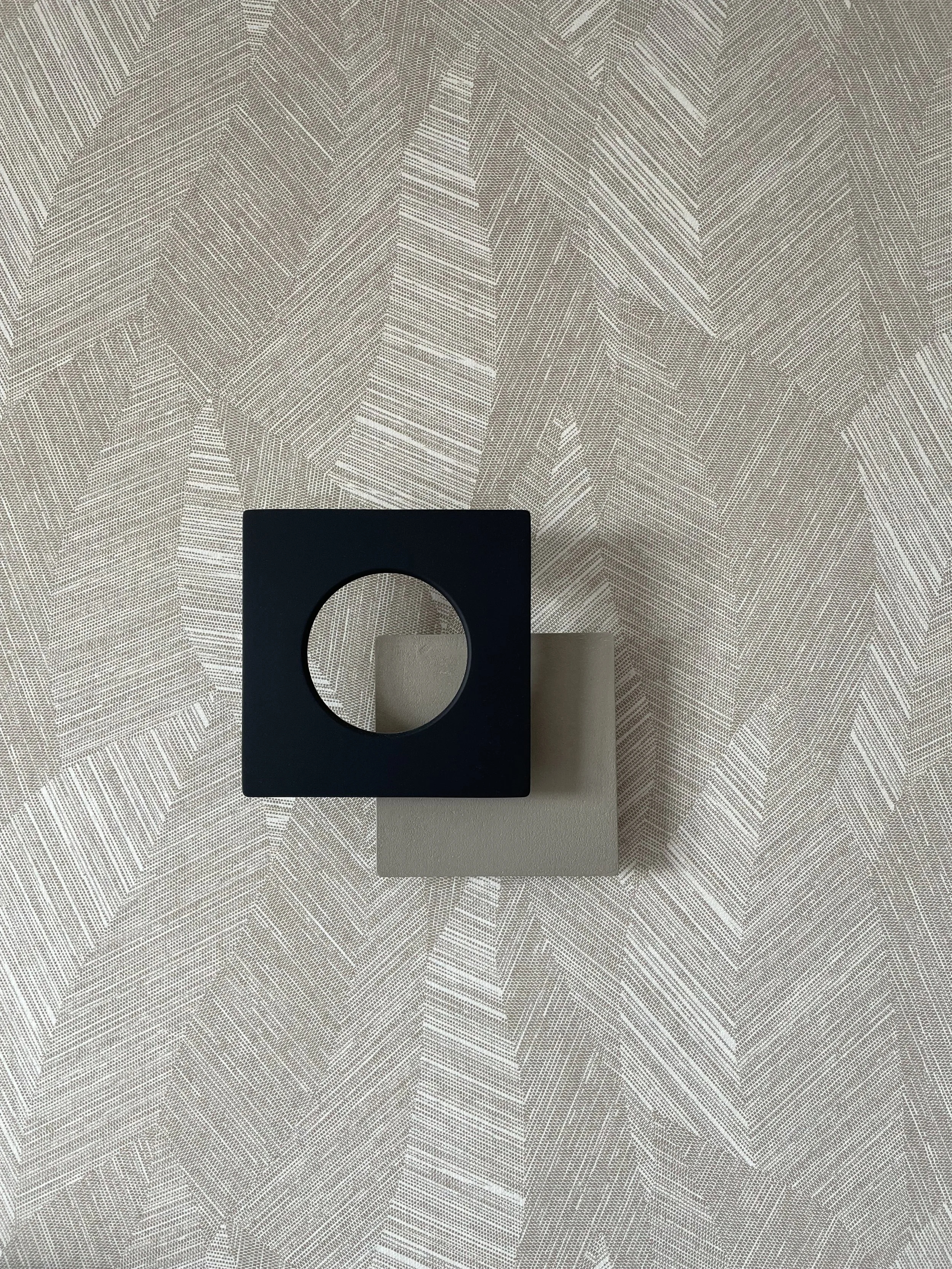 Détail de décoration intérieure moderne aux tons beige et noir, objets design sur textile à motif, ambiance élégante par décoratrice d’intérieur à Annecy.