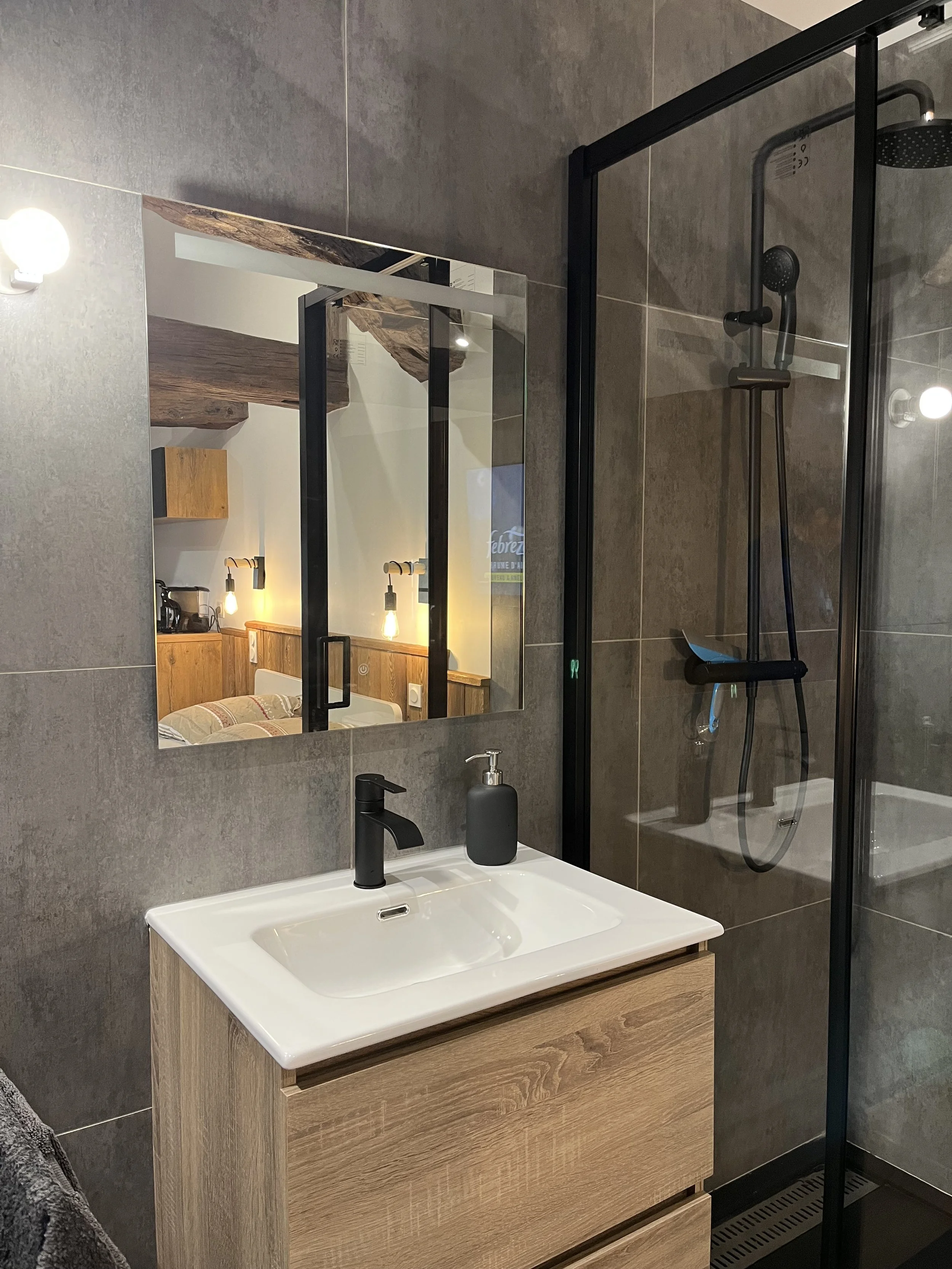Aménagement de salle de bain moderne avec bois et noir, douche vitrée et mobilier sur mesure, projet de décoration intérieure à Annecy ou en accompagnement à distance.