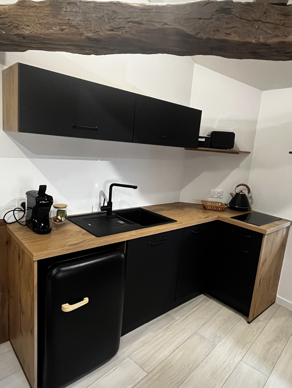 Cuisine moderne compacte avec plan de travail en bois et finitions noires, optimisation d’un petit espace sous pente, projet d’aménagement intérieur à Annecy et à distance.