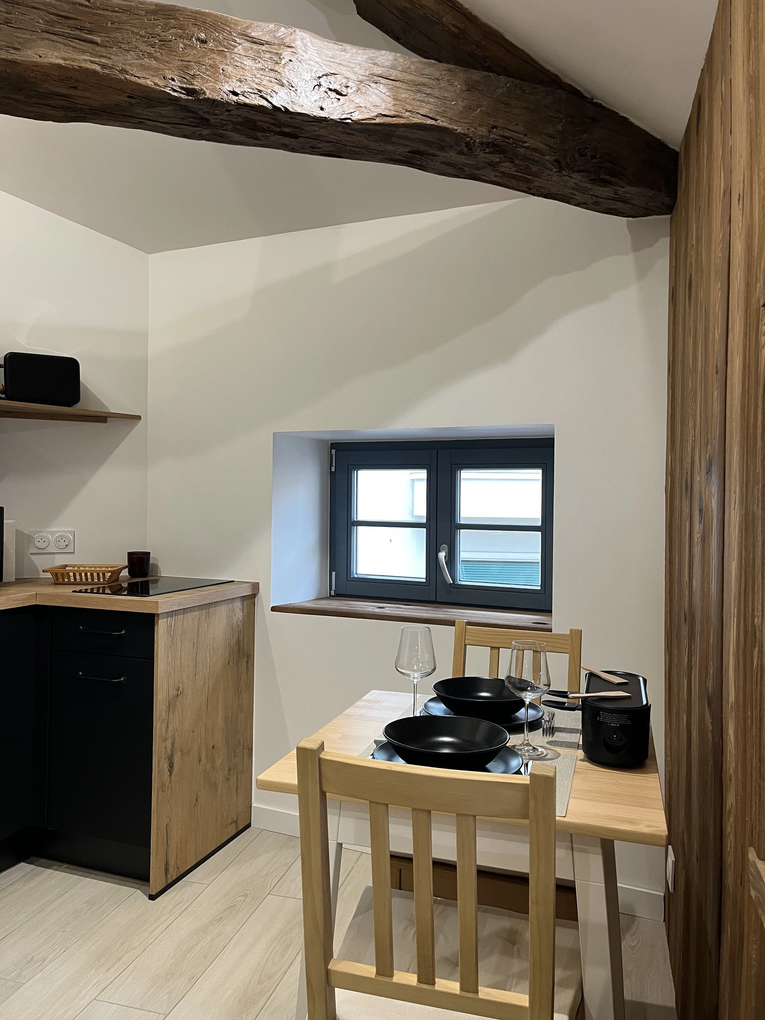 Cuisine chaleureuse avec bois et poutres apparentes, aménagement intérieur optimisé et décoration sur mesure, projet réalisé à Annecy ou en accompagnement à distance.
