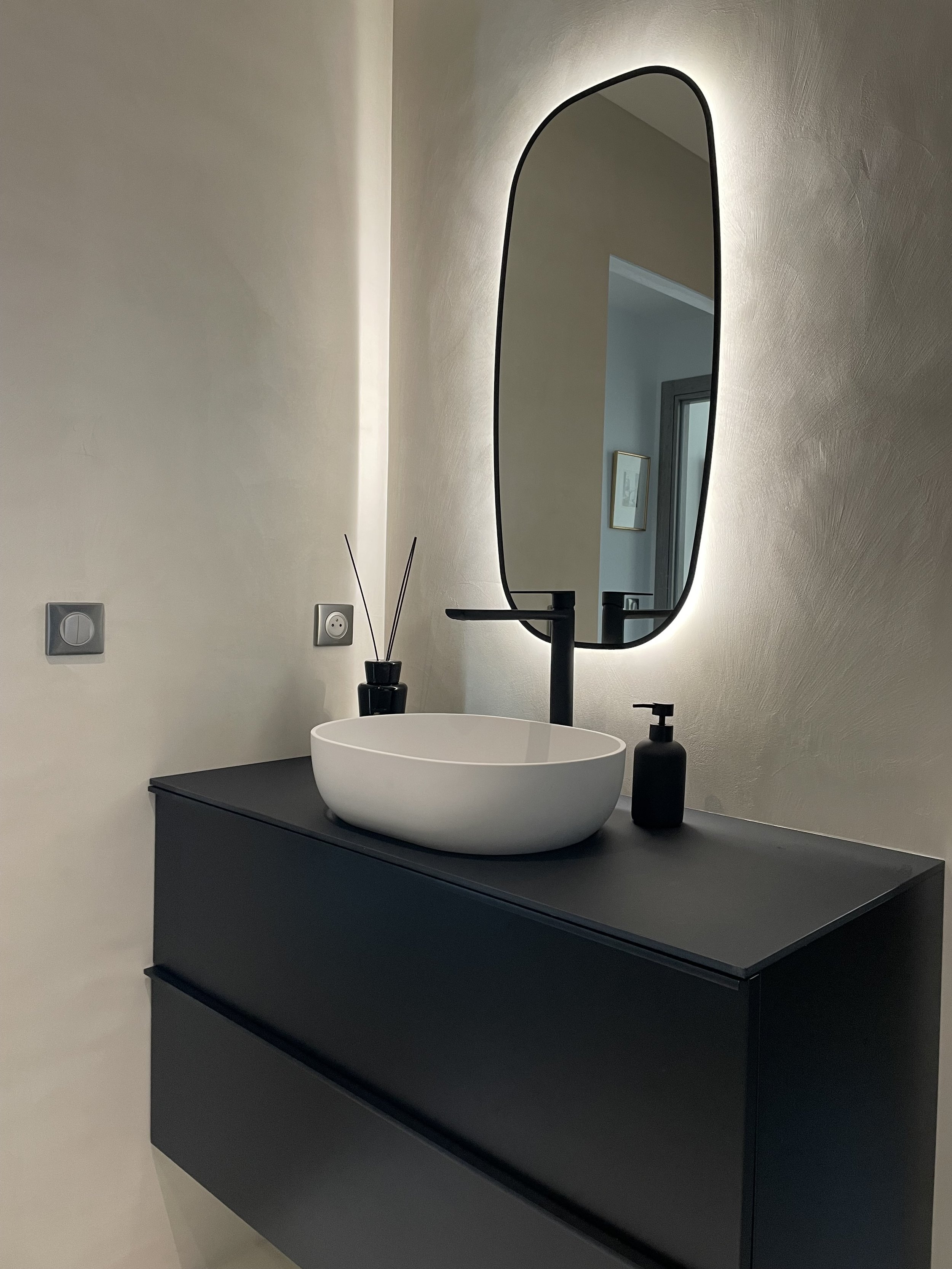 Décoration de salle de bain moderne noir et beige, meuble vasque design et miroir éclairé, projet d’aménagement intérieur à Annecy.
