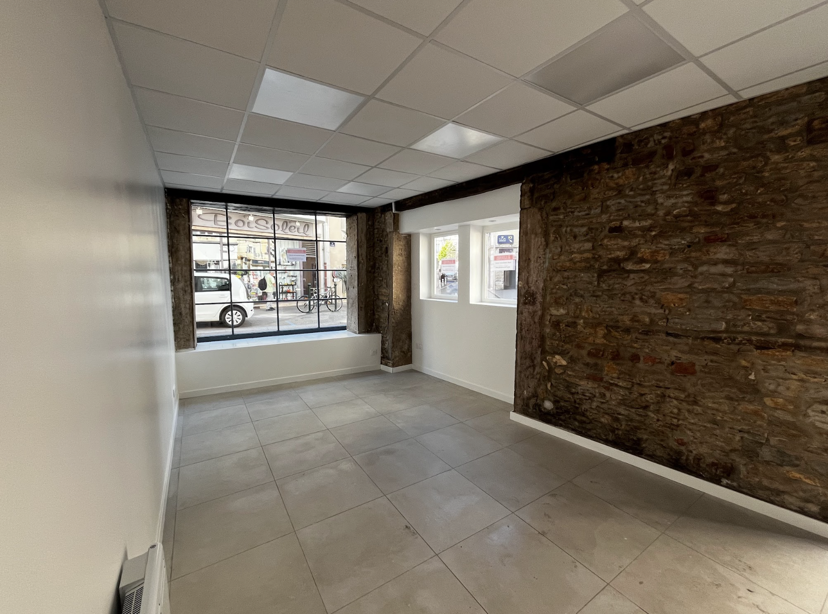 Local commercial vide avec mur en pierre et belle luminosité, projet d’aménagement et de rénovation d’espace professionnel à Annecy ou en accompagnement à distance.