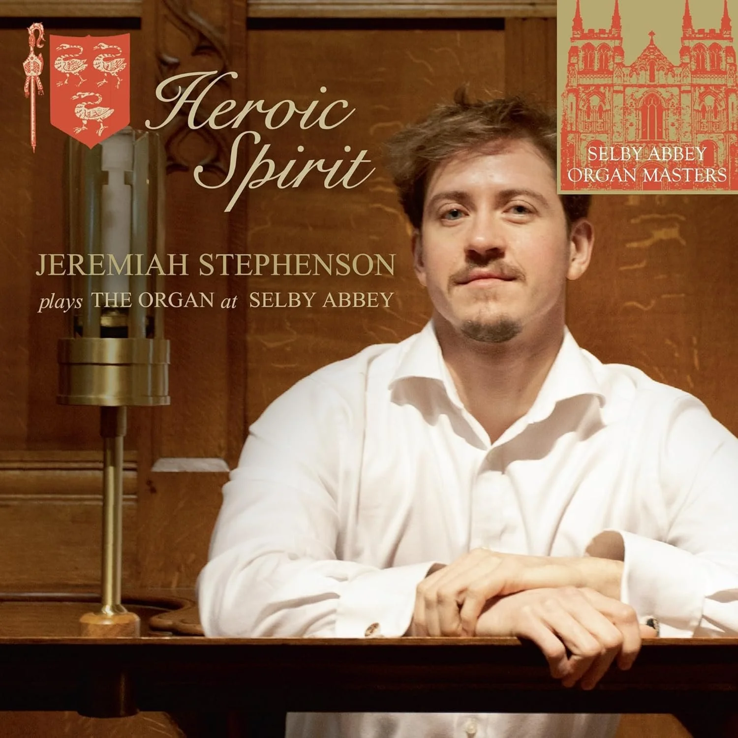 Promotional poster featuring Jeremiah Stephenson sitting at a wooden desk with a white shirt, promoting a performance of "Heroic Spirit" at Selby Abbey, showcasing a logo of Selby Abbey Organ Masters in the top right corner.
