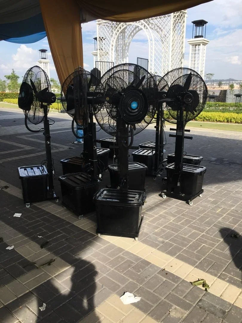 Multiple black stand fans outdoors on a paved area with decorative white arch and pillars in background.