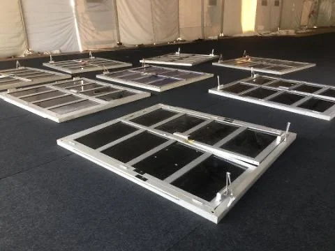 Several disassembled window frames laid out on a dark carpeted floor in a room with unfinished walls.