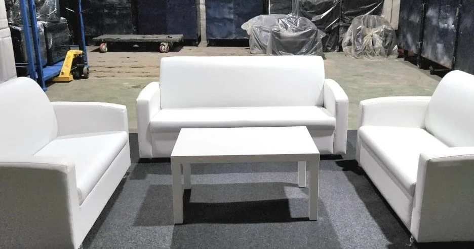 Three white sofas and a small white table in a warehouse setting.