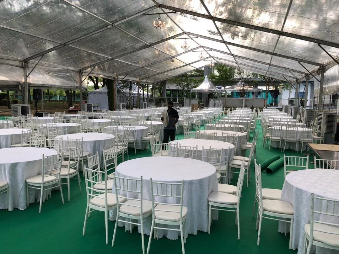 Empty event tent with round tables covered in white tablecloths and white chairs, set up for a gathering or banquet.