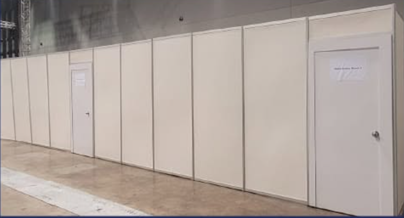 White partition walls with two doors in an indoor space, likely for an event or exhibition.