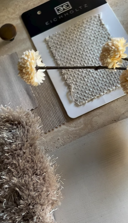 Stoffstalen en stoffen monsters, een tak met kunstbloemen, en een vachtband op een tafel.