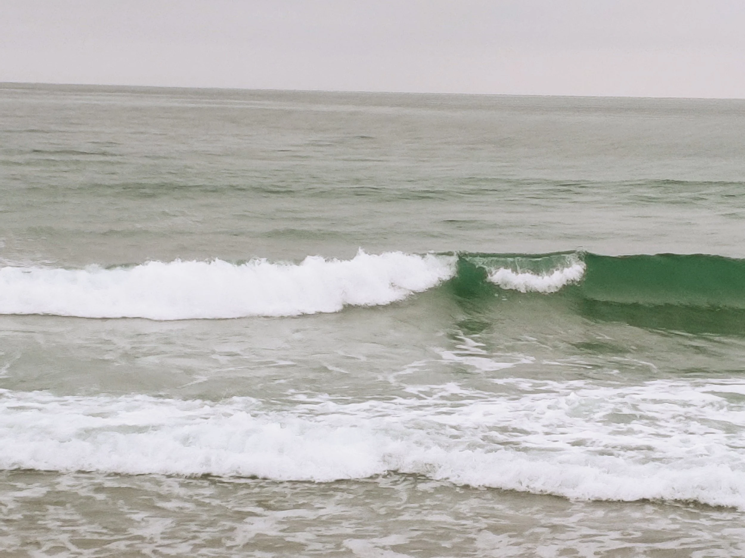 Overcast view of the ocean with small waves approaching the shore