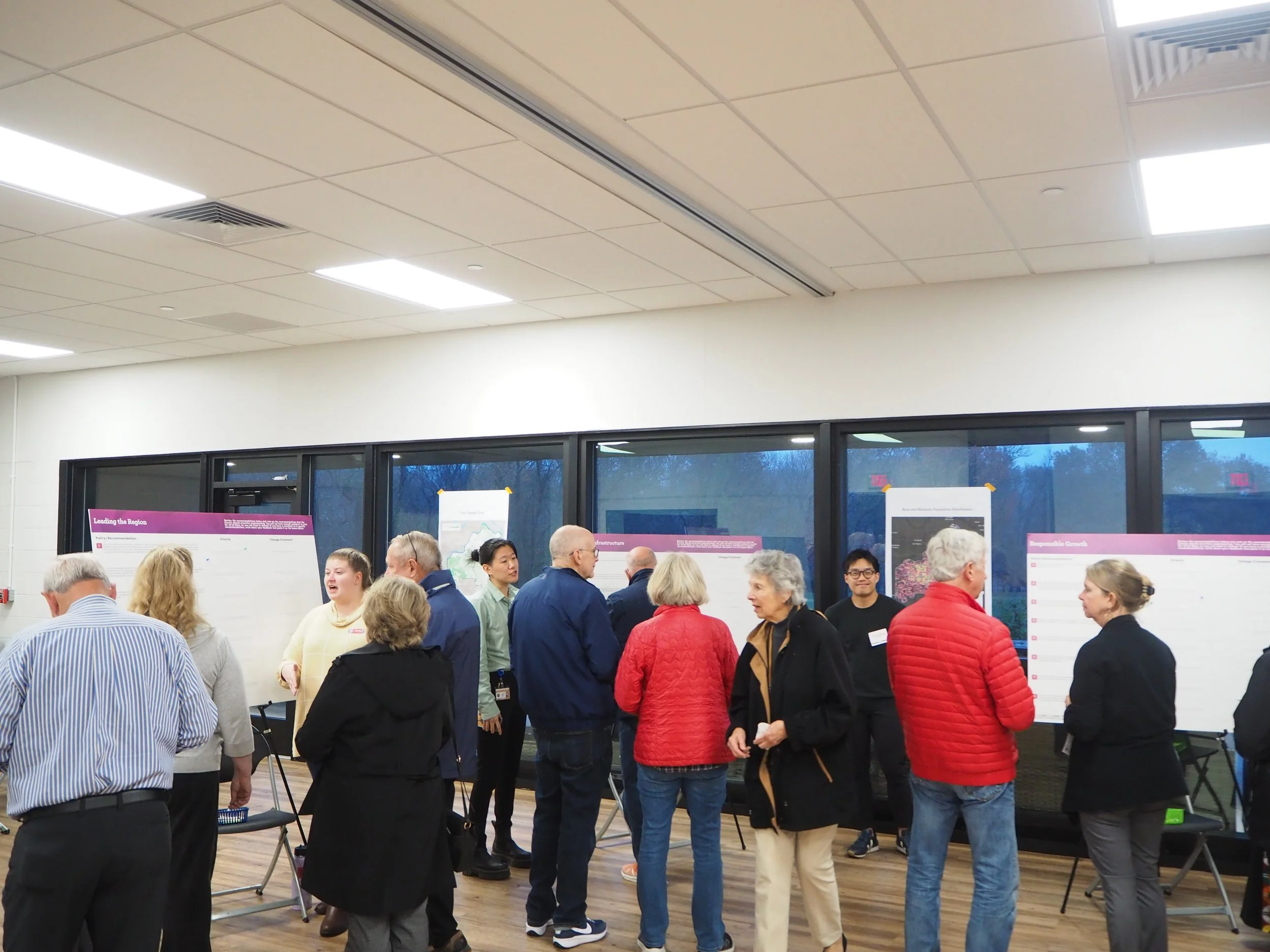 A group of people gathered in a room with large posters on display, engaging in conversation.
