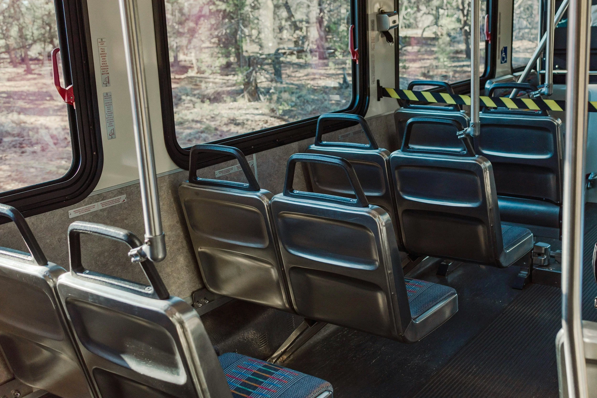 An inside view of a public bus with rows of empty metallic chairs