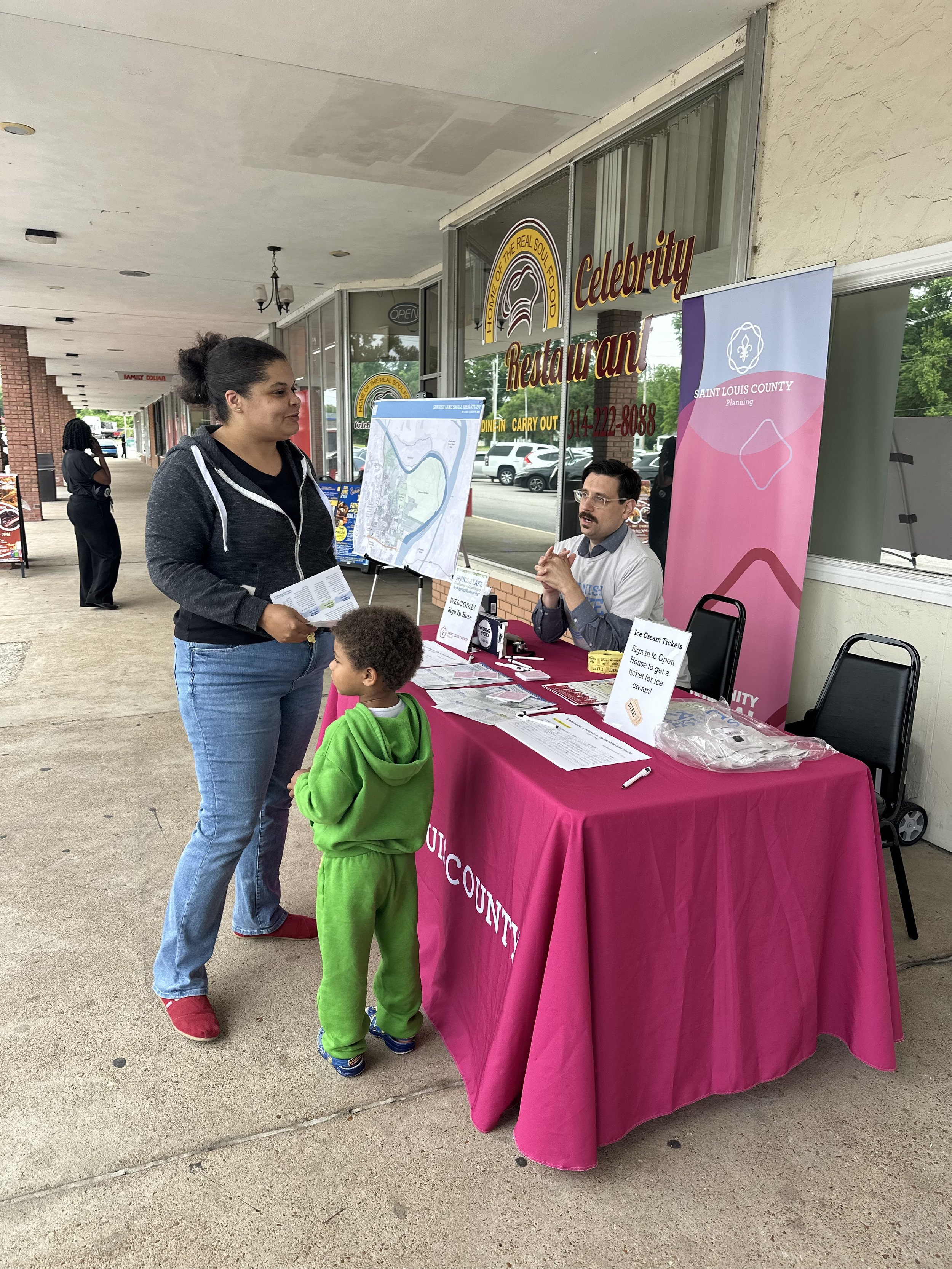 A parent and child sign into the Spanish Lake Open House 1 and speak with a St. Louis County representative at the sign-in table
