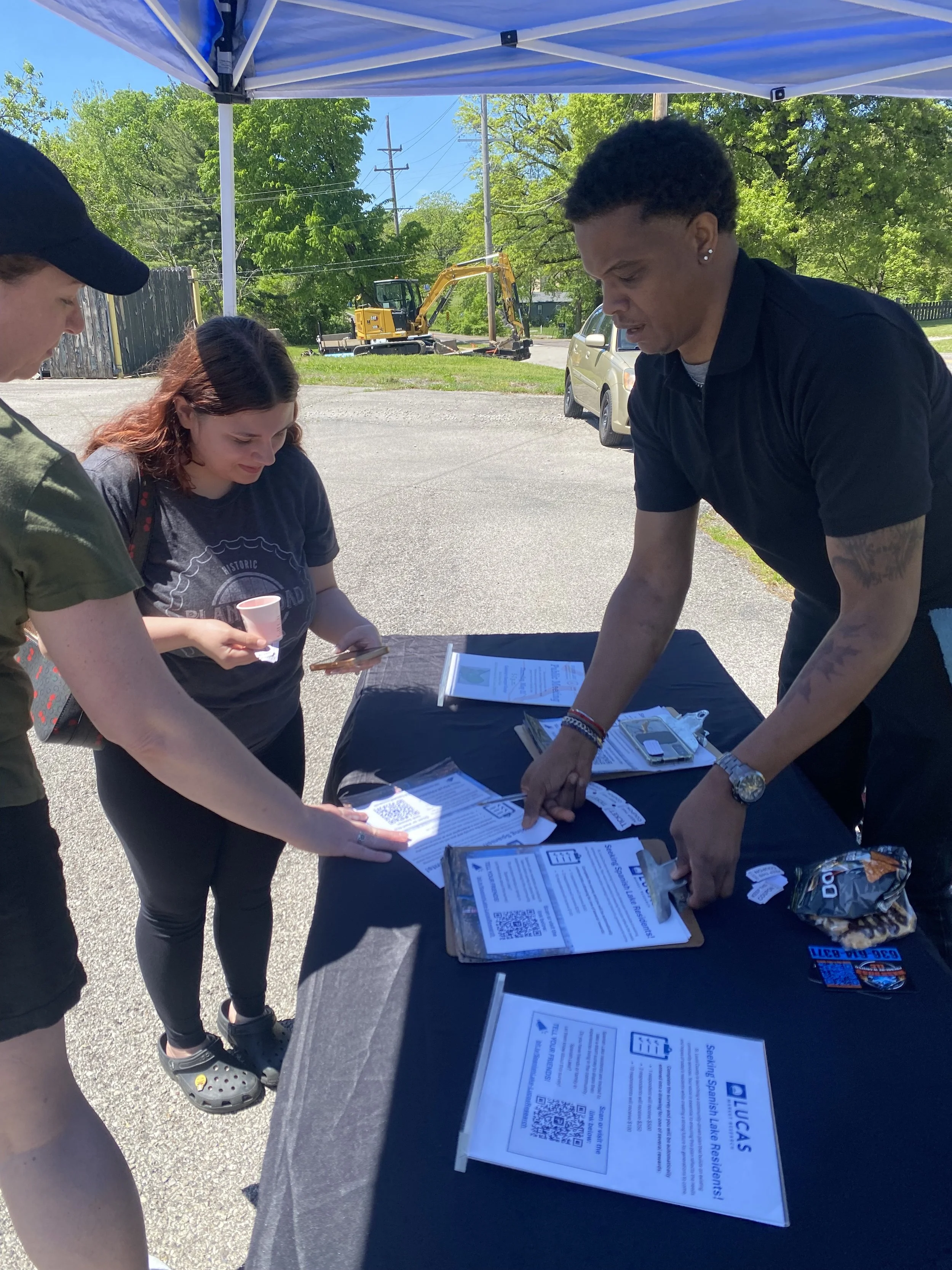 Two people fill out a survey at an outdoor table in Spanish Lake