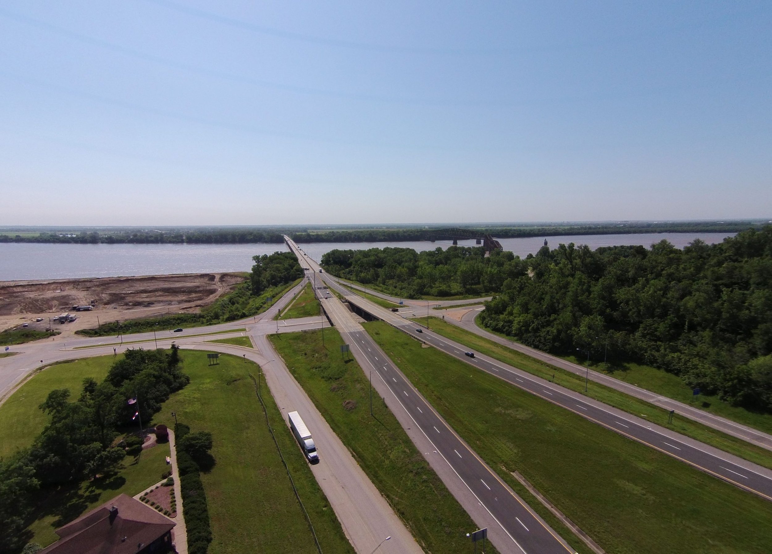 An image of the I-270 Riverview interchange reconstruction sight. A highway extends over a river and is intersected by a road with a substantial development area on one side.