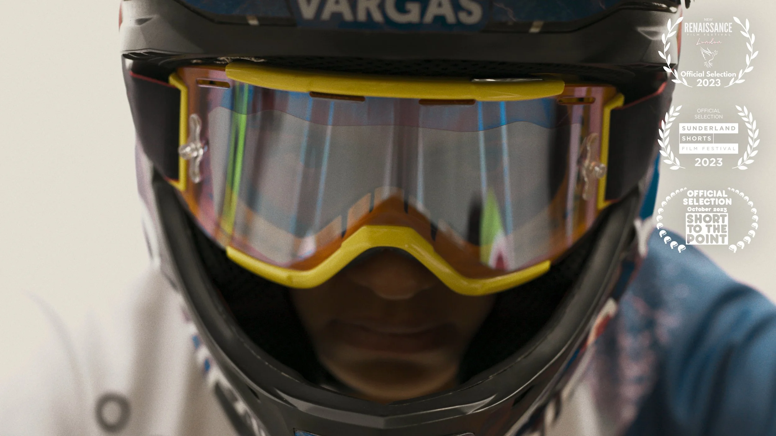 Close-up of a person wearing yellow-tinted ski goggles, a helmet with a partially visible logo, and a colorful patterned jacket.