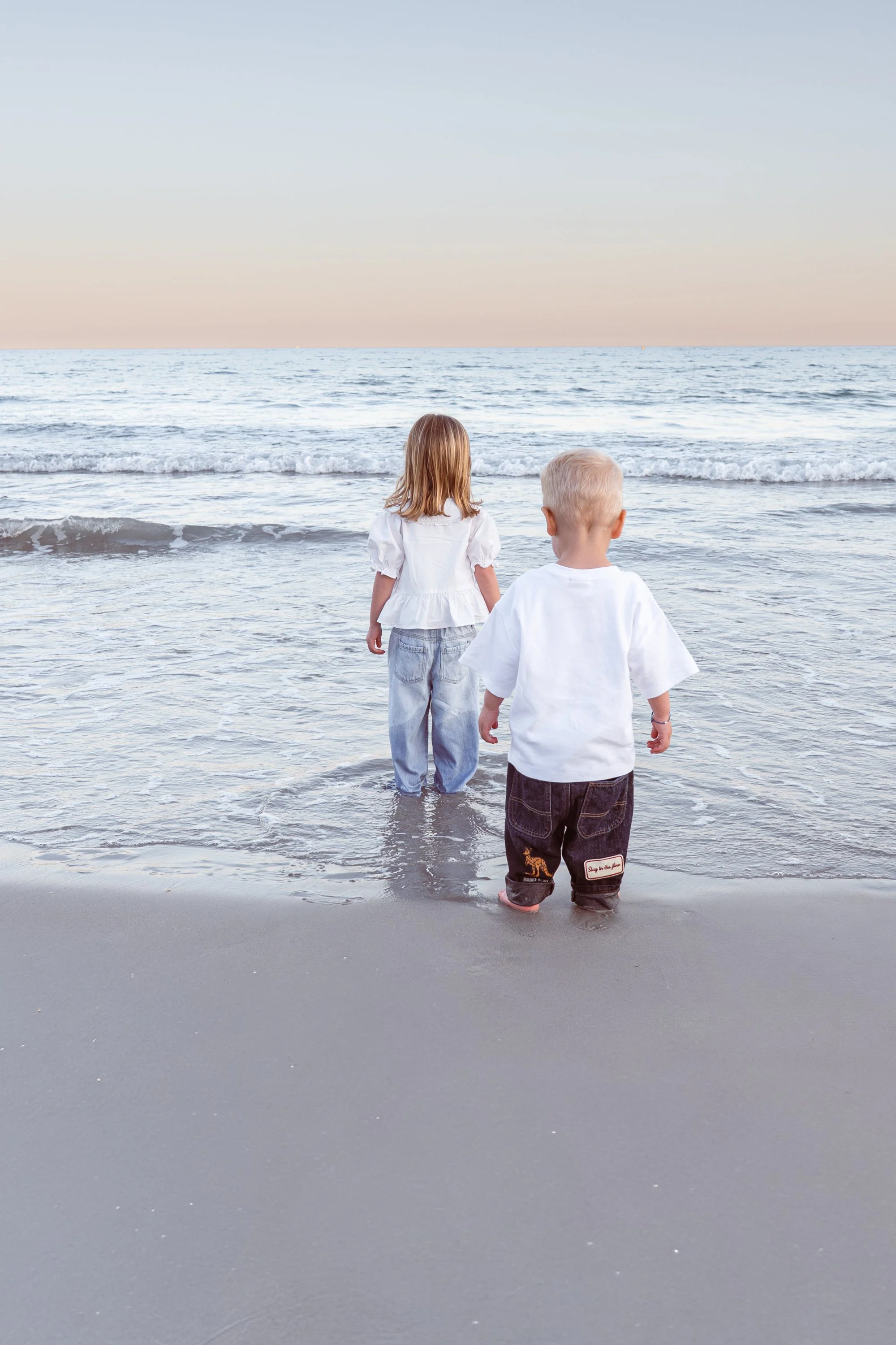 Photo de deux enfants regardent l'océan, debout dans l'eau à la plage en région PACA