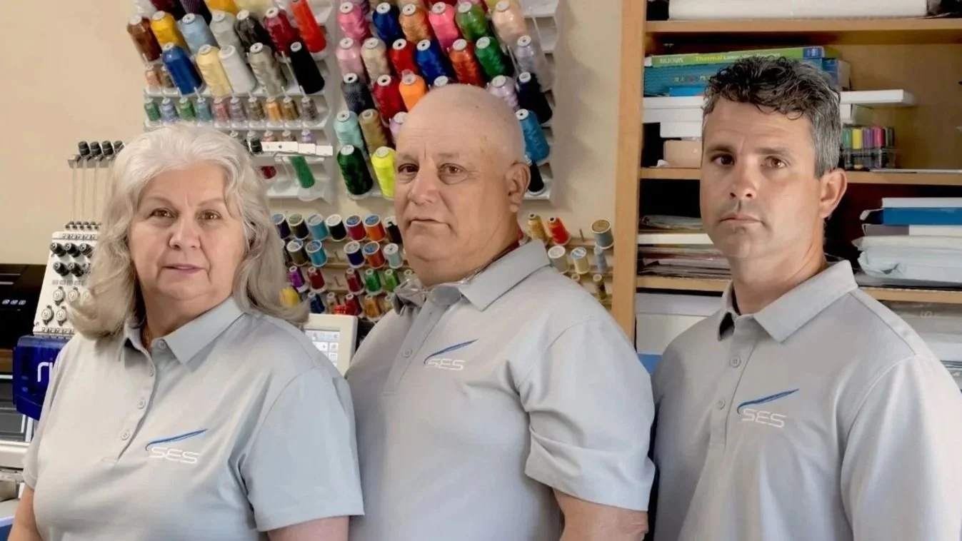 Equipo de SES Services con uniforms  bordado con logo y máquina bordadora en el  fondo