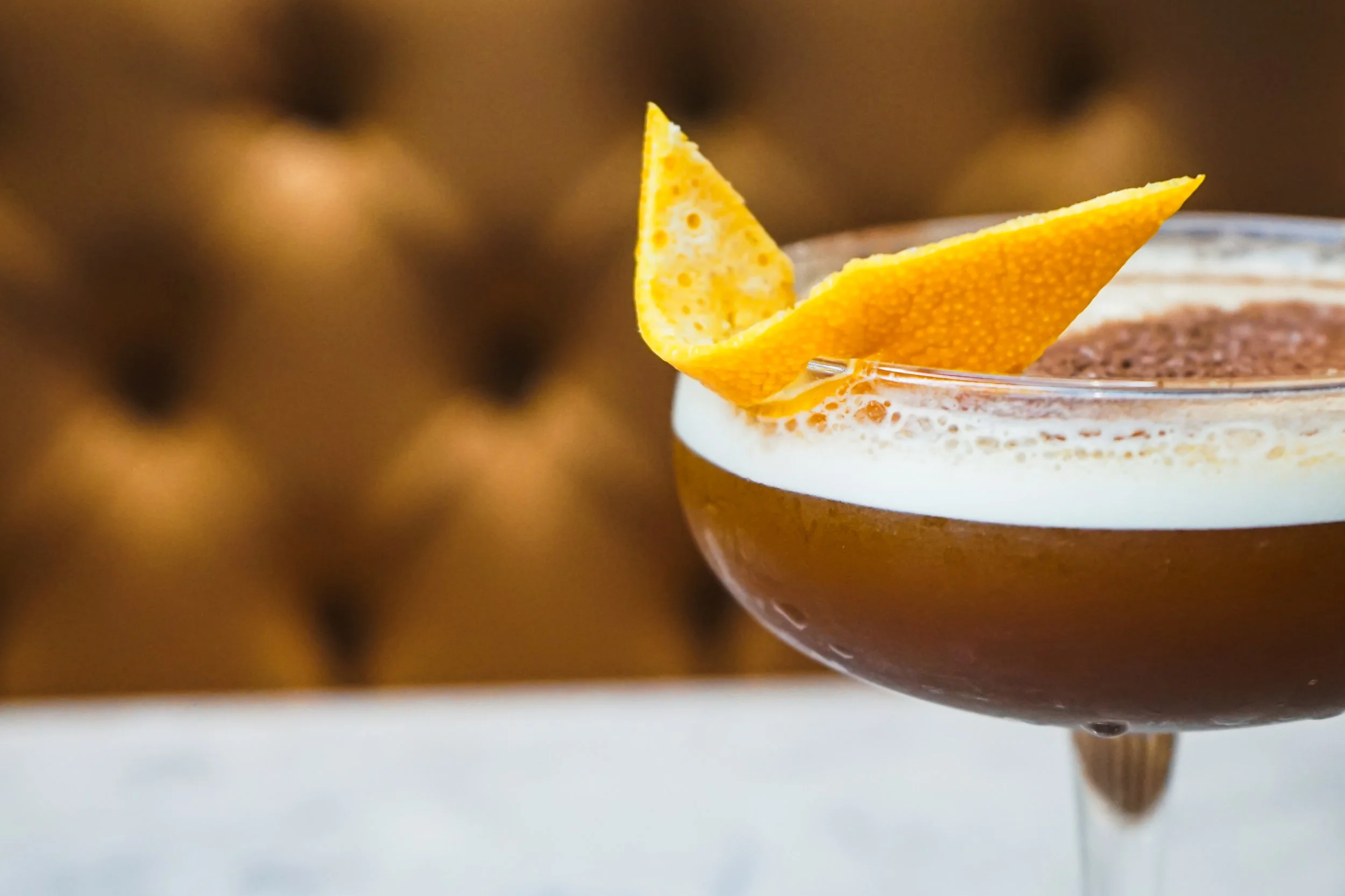 Close-up of a cocktail glass with a chocolate drink, garnished with a lemon peel twist.