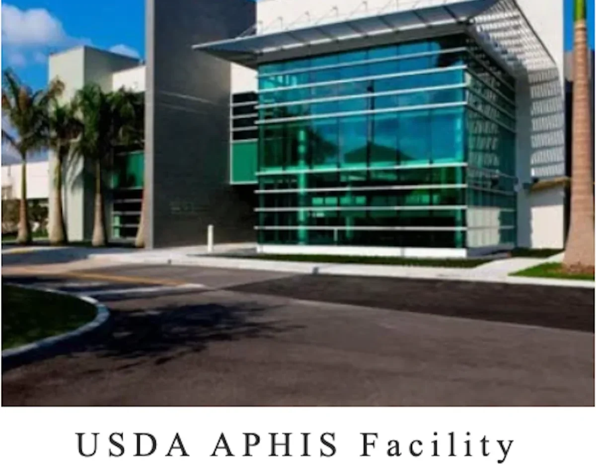 Modern office building with large glass windows and palm trees outside, labeled as USDA APHIS Facility.