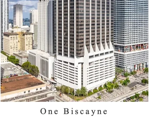 A cityscape featuring skyscrapers, with a prominent white building named One Biscayne. The scene includes palm trees and streets running through the city.