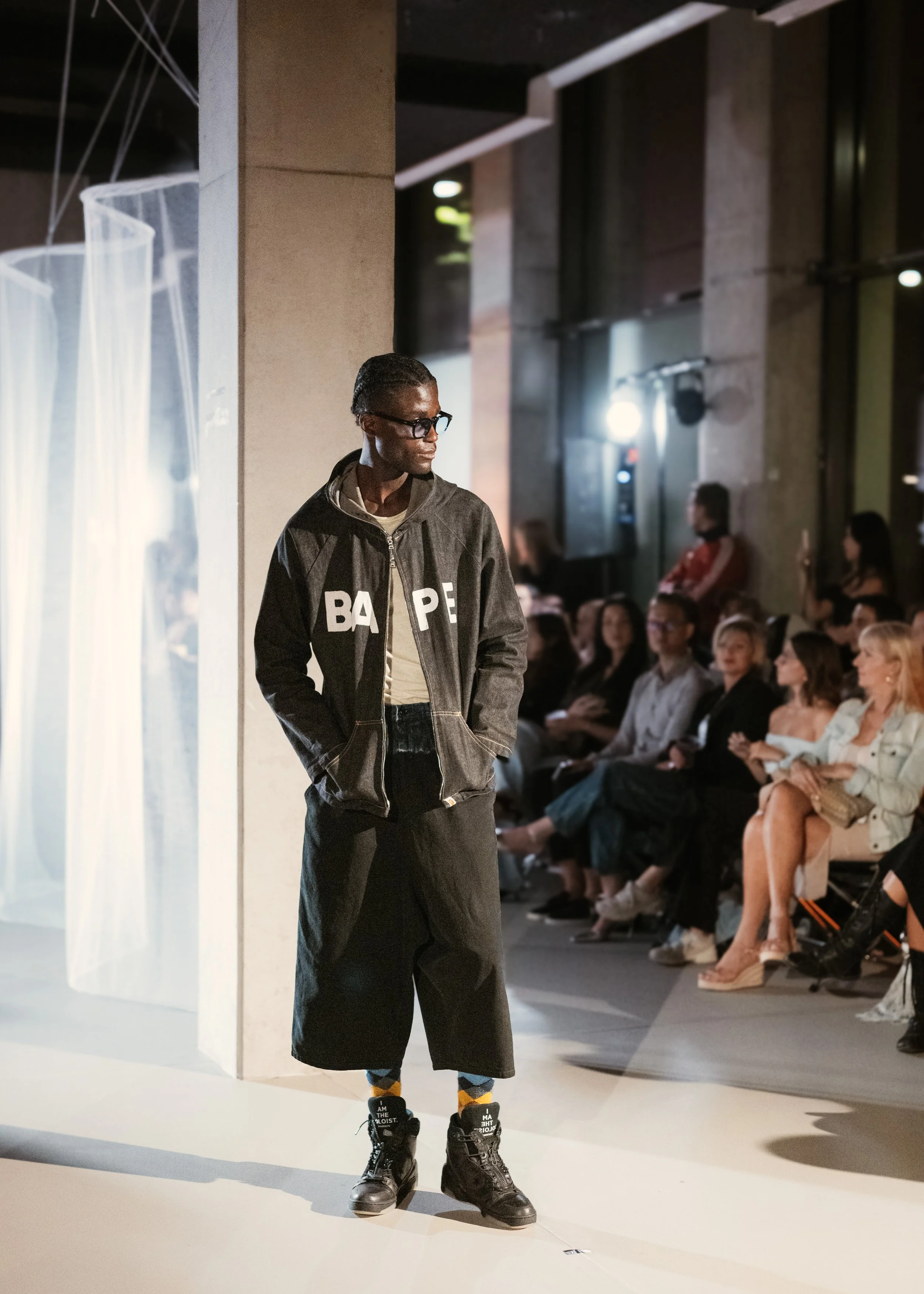 A key look from Amsterdam Fashion Week SS26. The model is wearing Denim Jacket (Bape), Vest (Yohji Yamamoto Y's), Denim Shorts (Yohji Yamamoto Y's) and Shoes (Converse x The Soloist).