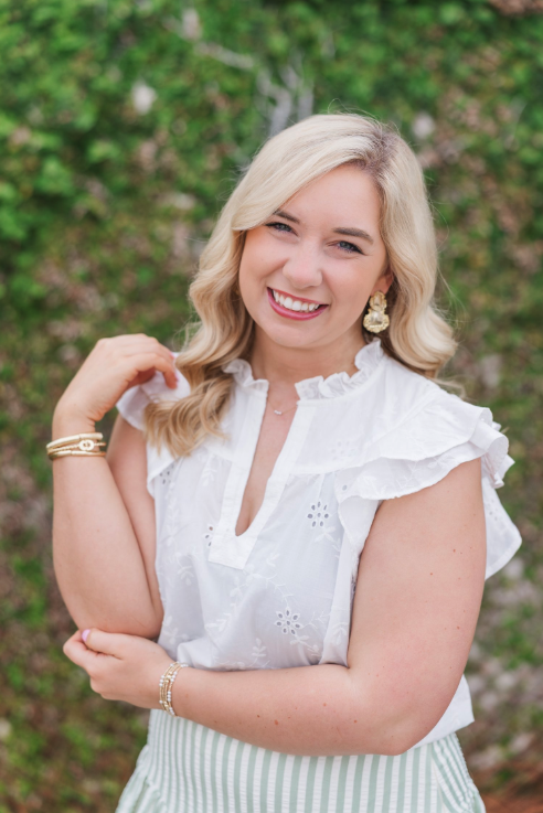 A smiling woman with blonde hair in a white top on the Megan Mae Events team.