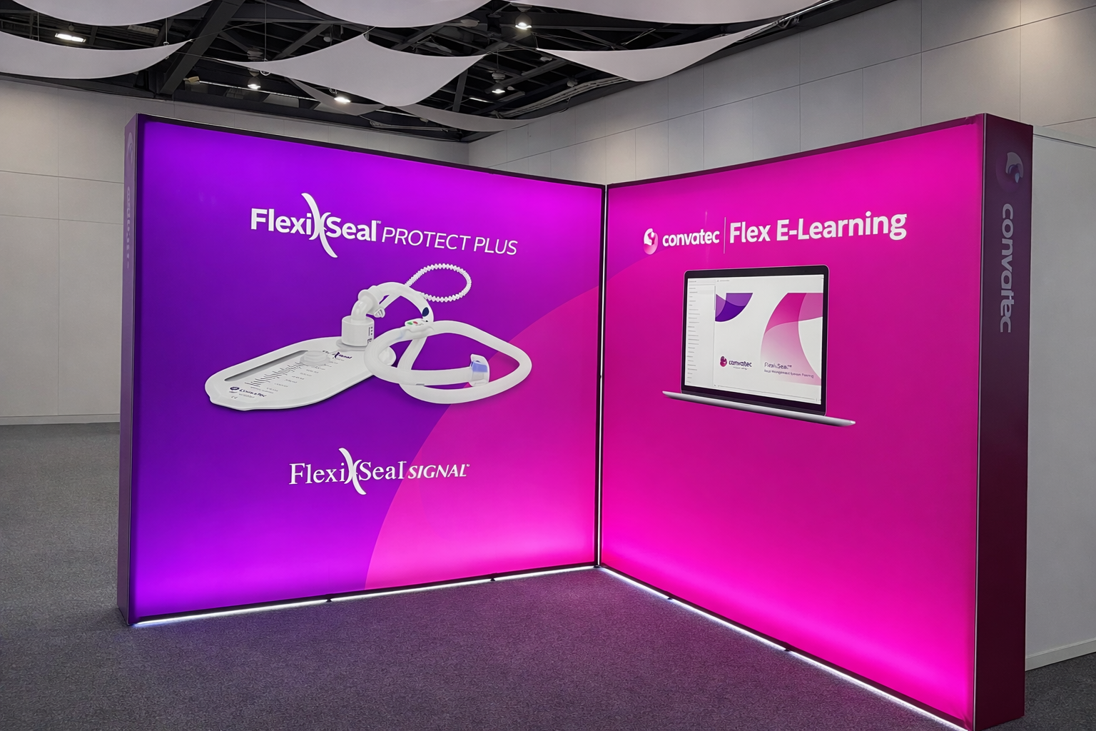 Trade show display with purple and pink panels showcasing FlexiSeal Protect Plus, Signal, and E-Learning products from Convatec, featuring medical tubing, seals, and a laptop screen.