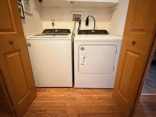A laundry area with a washing machine on the left and a dryer on the right, located between two wooden doors.