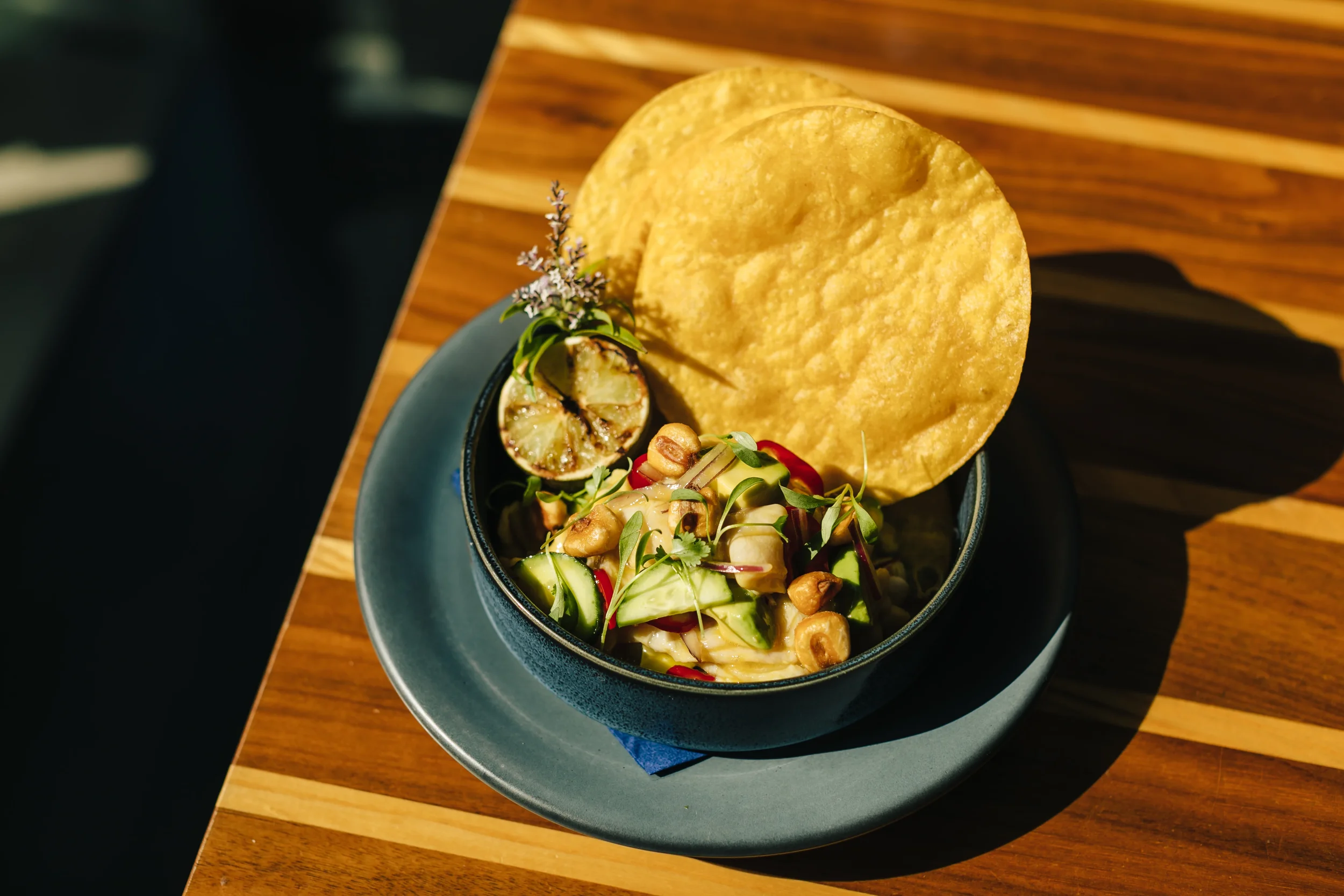 Vibrant ceviche garnished with herbs, lime, and nuts, served with two crispy tostadas.