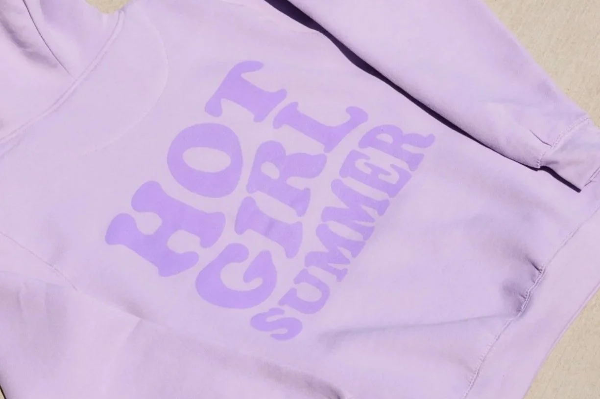 A lavender hoodie with the words 'Stay Cozy' in stylized purple lettering printed on the front.