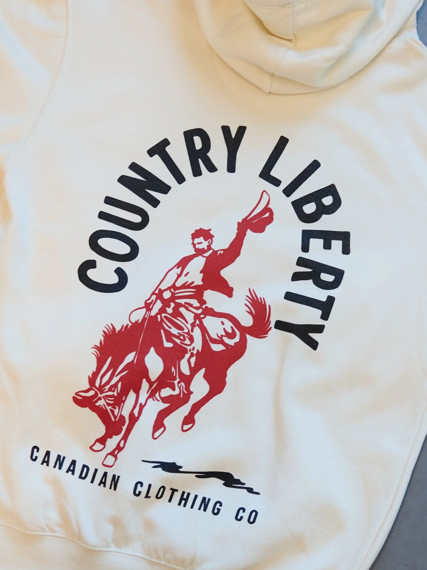 White hoodie with a graphic design of a man riding a horse, pointing forward, with the text 'Courtyard Library' arched above and 'Canadian Clothing Co' below.