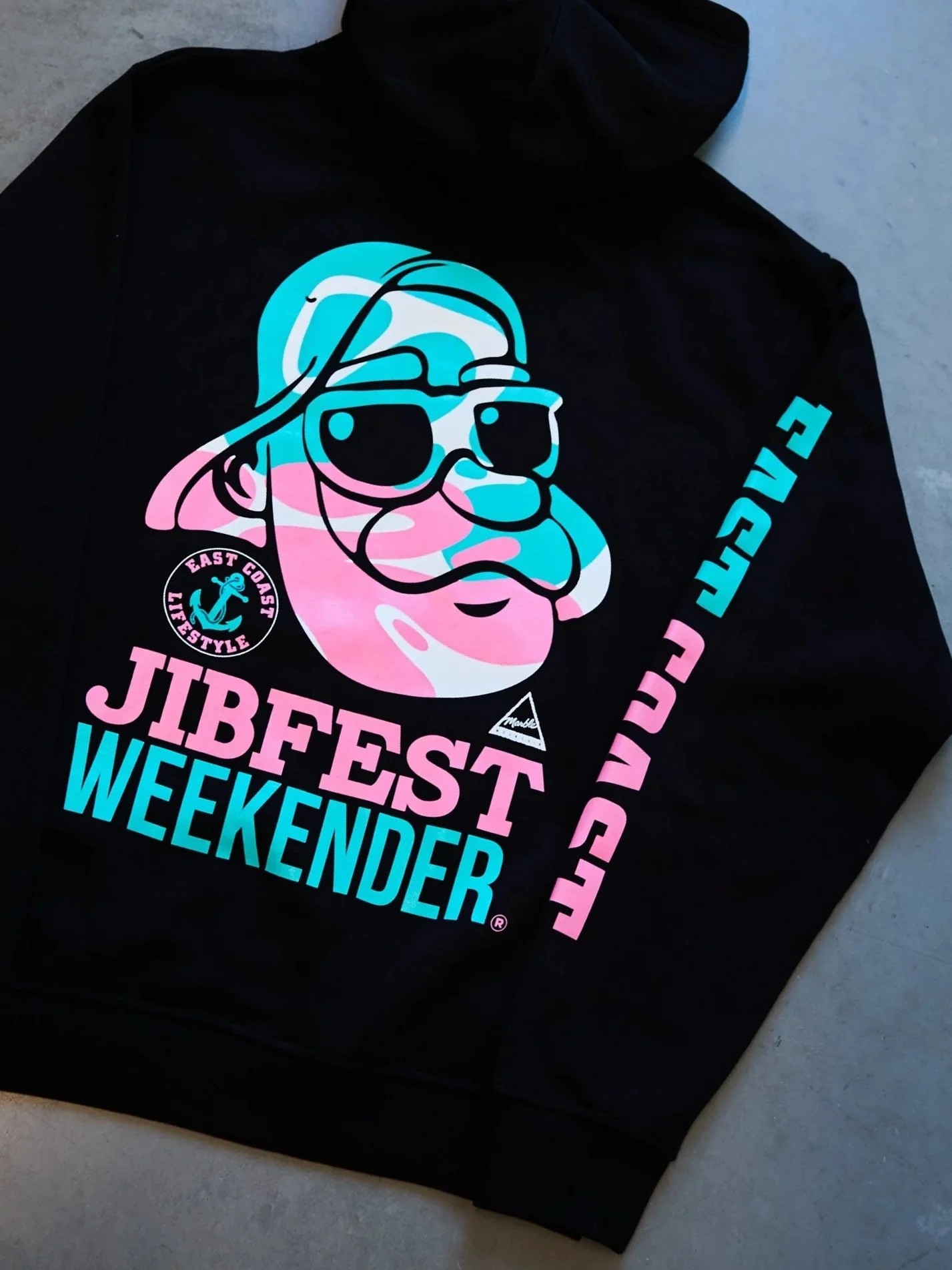 Black hoodie with a colorful graphic of a dog wearing sunglasses and a cap, with text that reads "JIBFEST WEEKENDER" in pink and blue, and additional smaller text and symbols related to a summer event